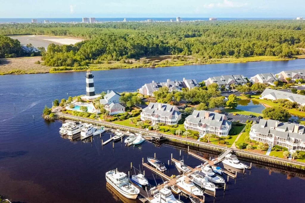 A scenic marina with a lighthouse and houses near the water. Enjoy the view of Little River SC.